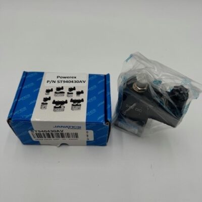 A Powerex Drain Valve DSP-DR-24VDC (P/N ST940430AV) box in blue and white sits next to a black electrical component wrapped in clear plastic on a white surface.