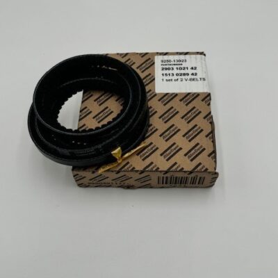 An Atlas Copco V-Belt (P/N 2903 1021 42) is coiled and placed atop a brown patterned box with a white label listing part numbers and "1 set of 2 V-BELTS," all on a plain white surface.