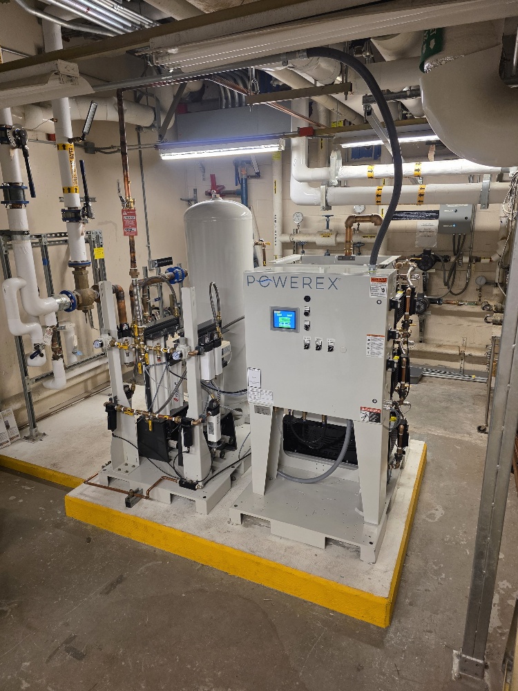 Powerex industrial air compressor system with a digital display and connected filtration tanks in a utility room.