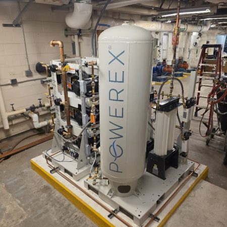A Powerex industrial air compressor system mounted on a yellow-bordered concrete base in a utility room.