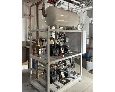 A two-tier industrial pump system with a horizontal pressure tank mounted on top, installed in a mechanical room.